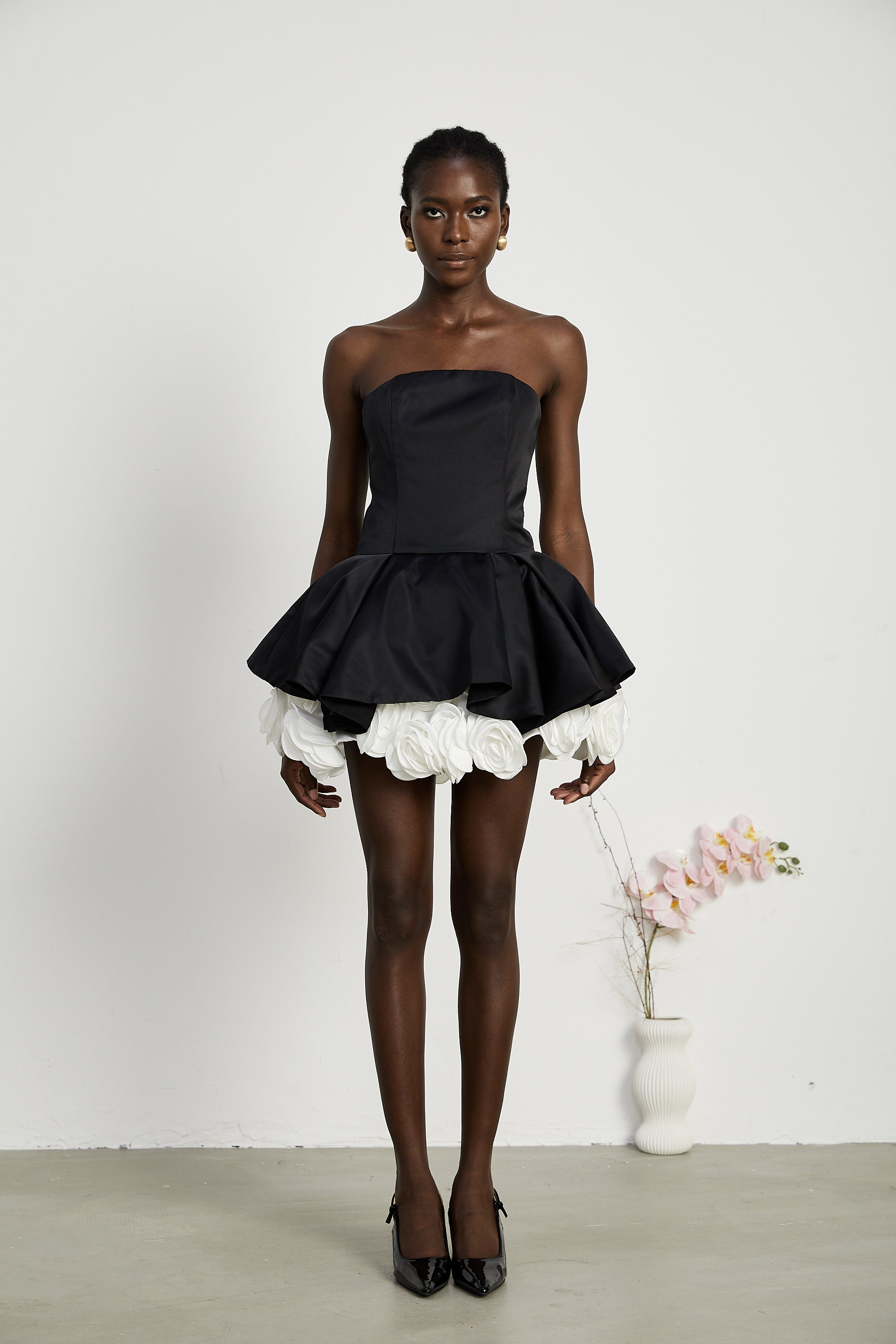 فستان لوسي الأسود القصير بدون حمالات مع طبقات من بتلات الزهور