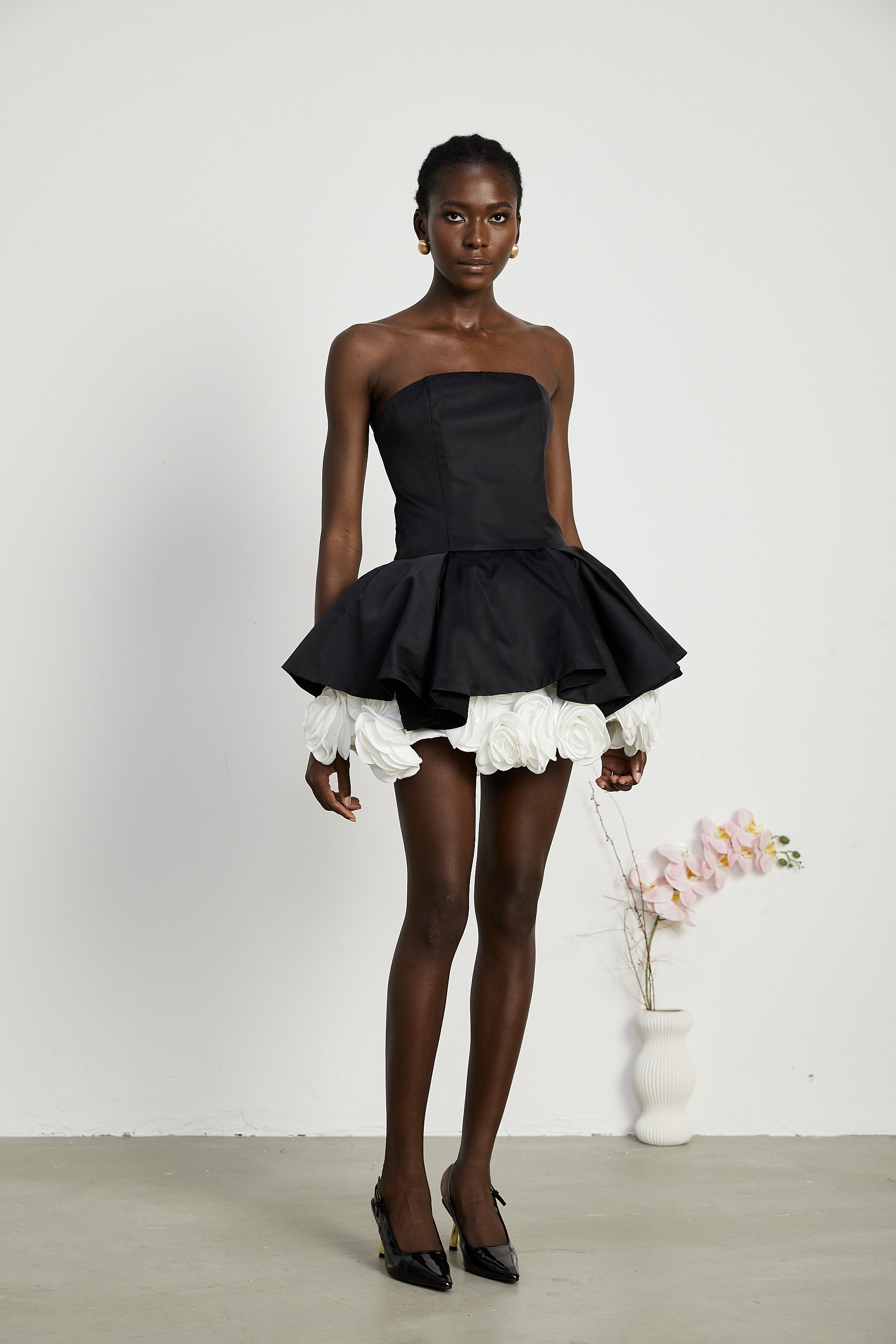 فستان لوسي الأسود القصير بدون حمالات مع طبقات من بتلات الزهور