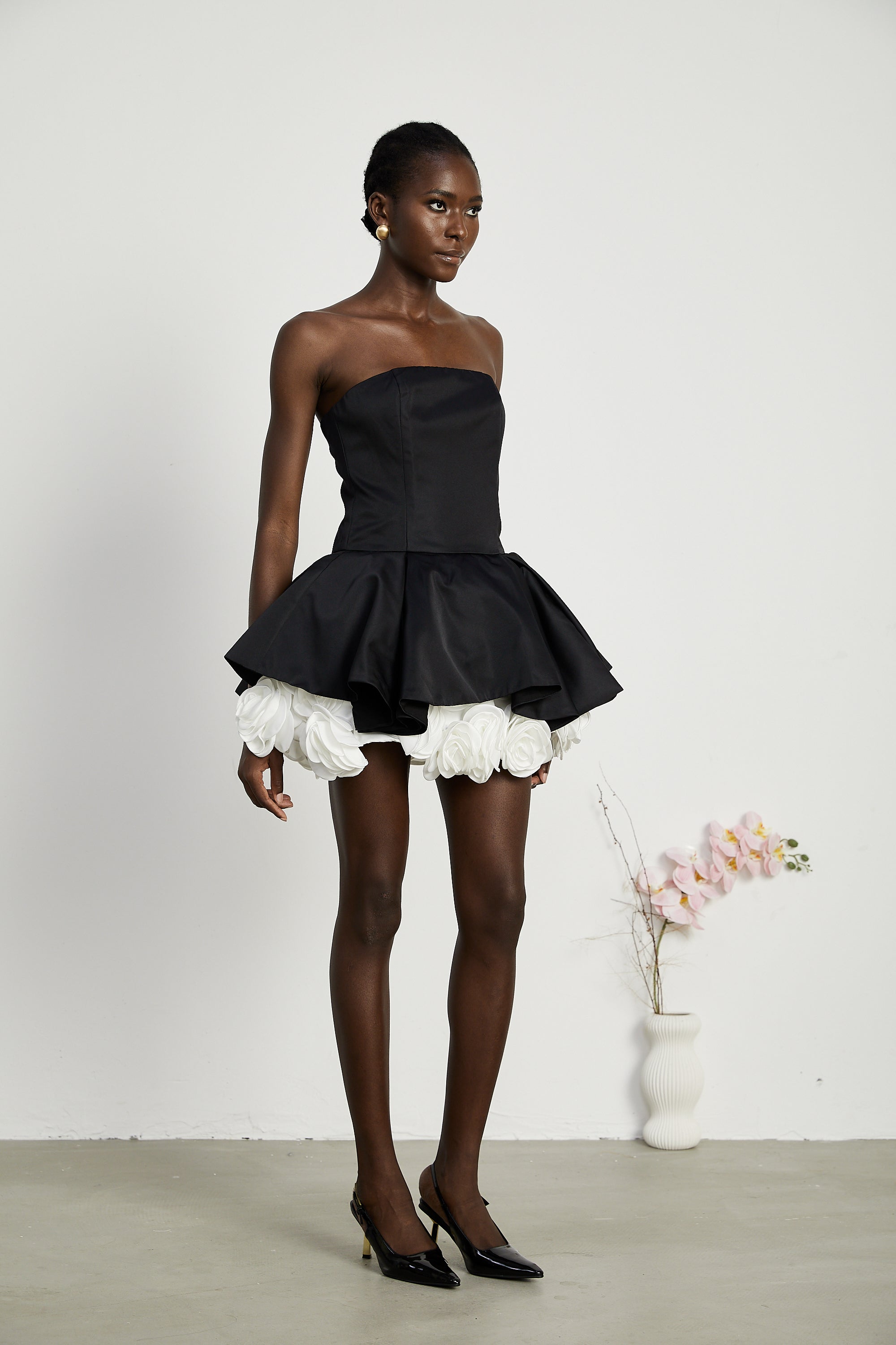 فستان لوسي الأسود القصير بدون حمالات مع طبقات من بتلات الزهور