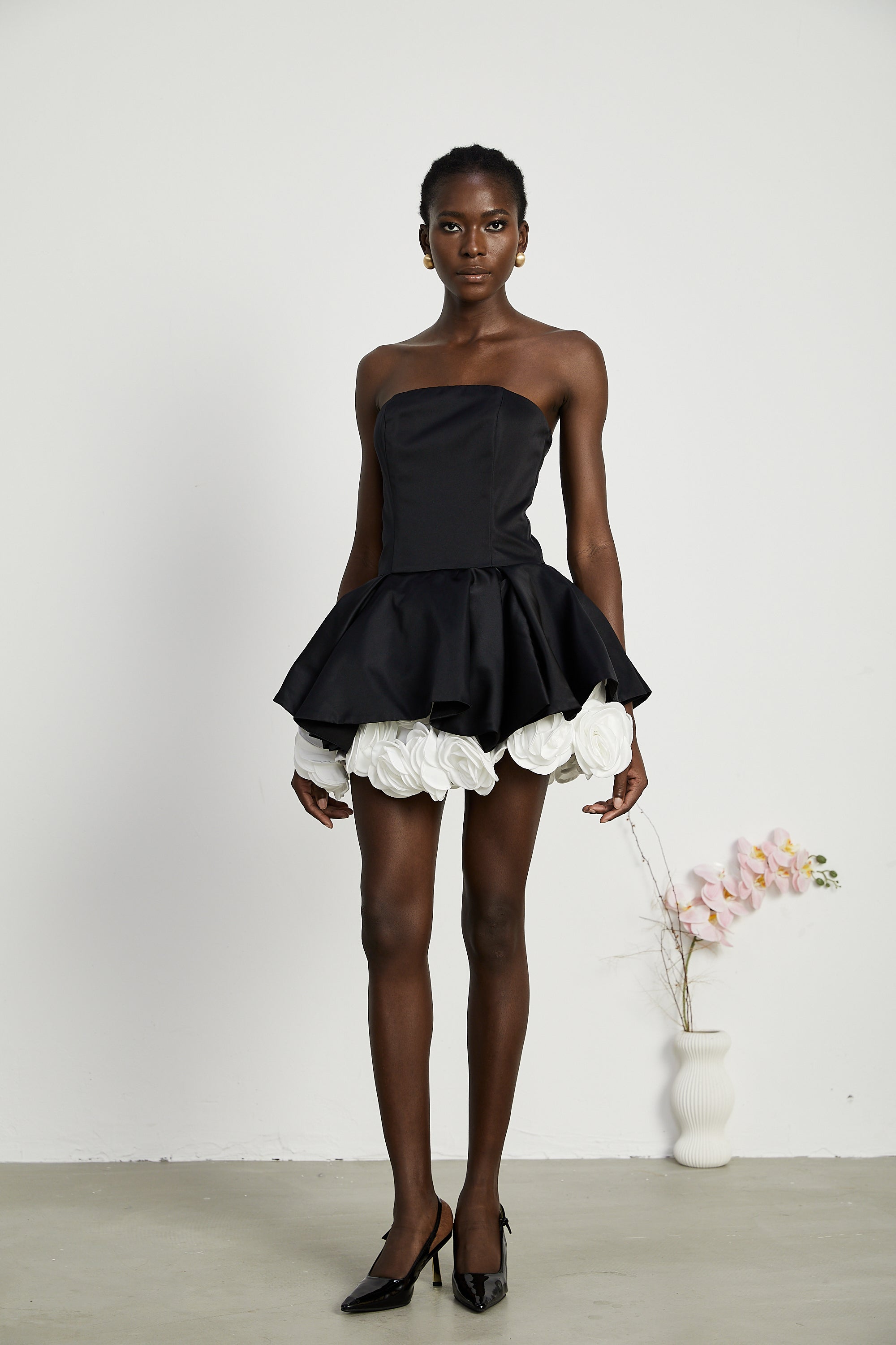 فستان لوسي الأسود القصير بدون حمالات مع طبقات من بتلات الزهور