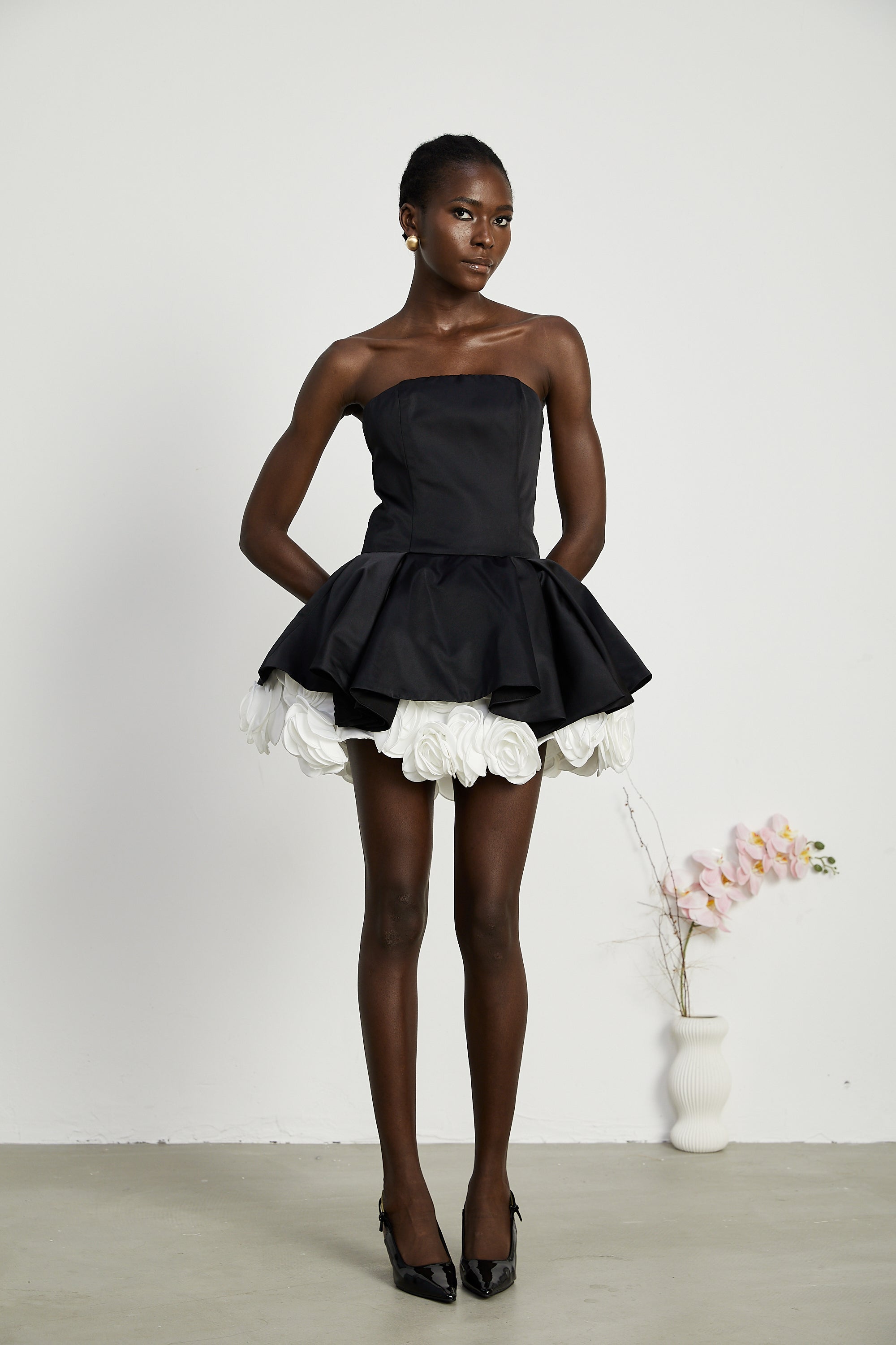 فستان لوسي الأسود القصير بدون حمالات مع طبقات من بتلات الزهور