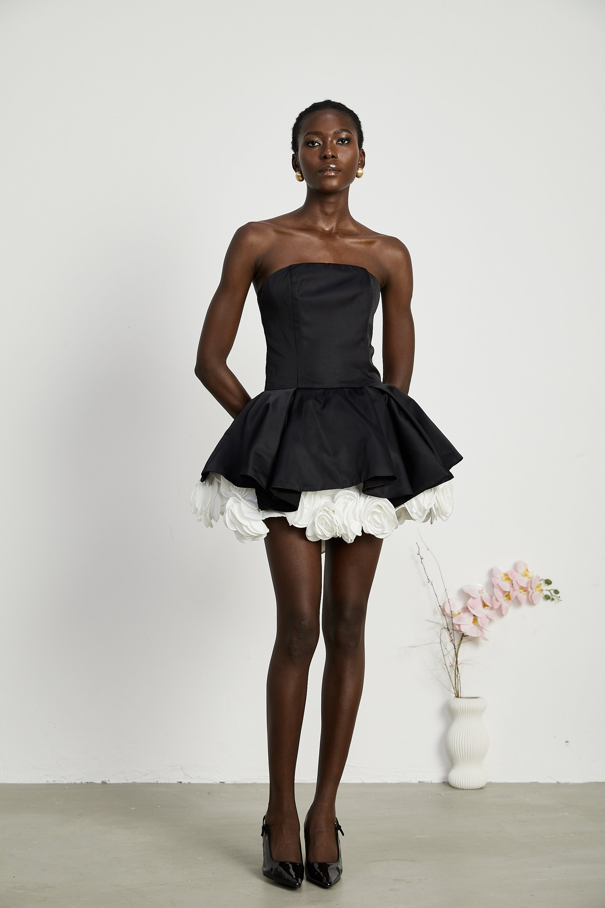 فستان لوسي الأسود القصير بدون حمالات مع طبقات من بتلات الزهور