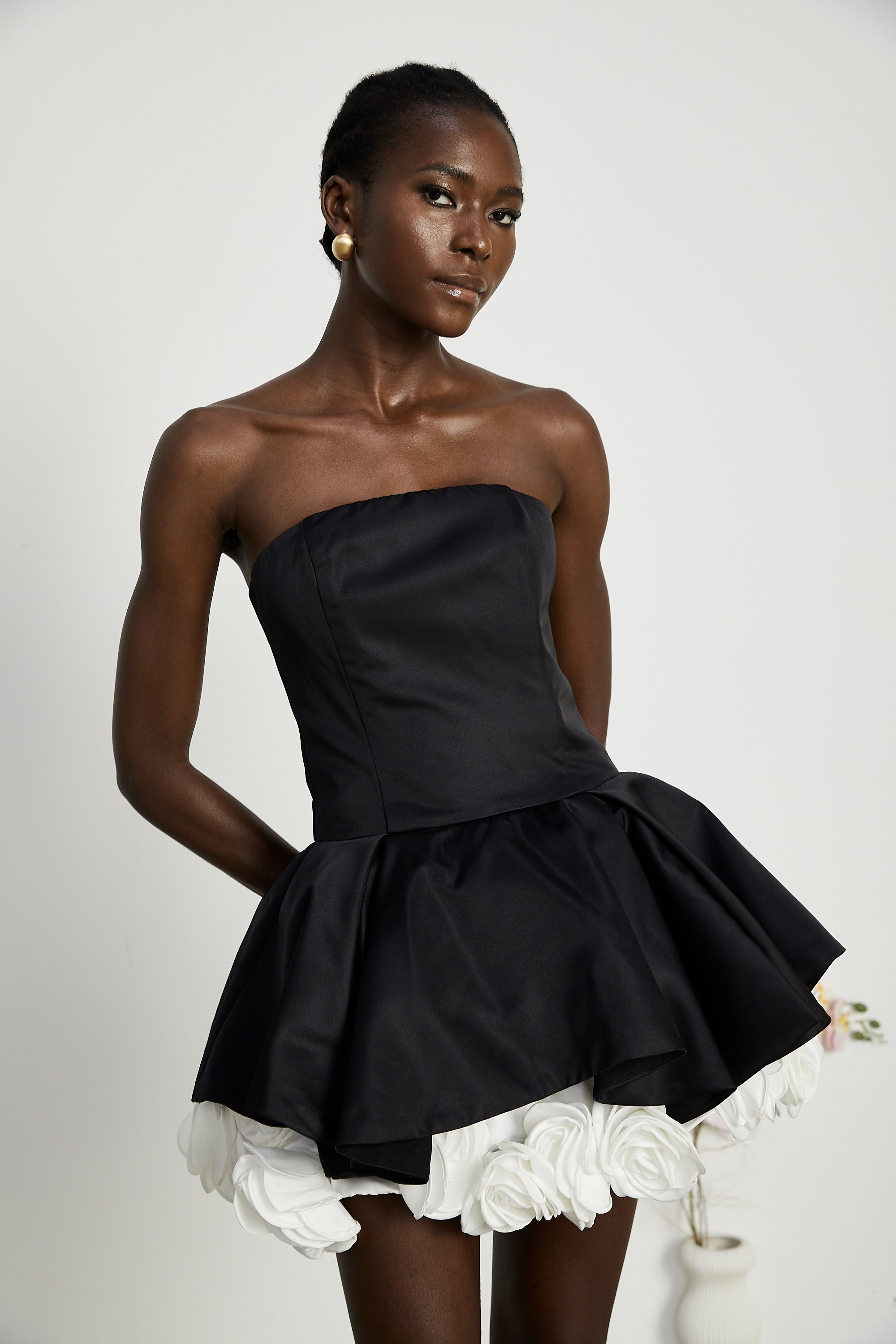 فستان لوسي الأسود القصير بدون حمالات مع طبقات من بتلات الزهور