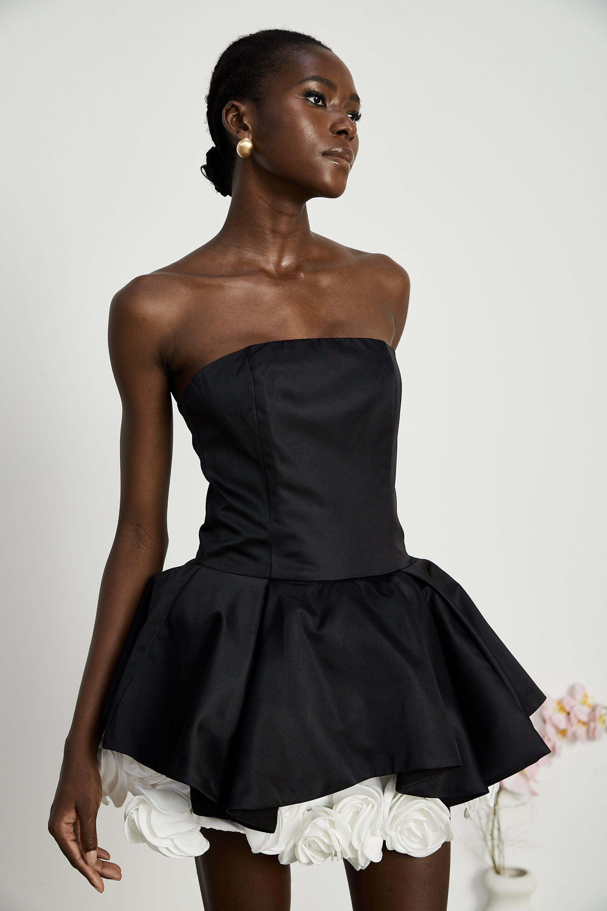 فستان لوسي الأسود القصير بدون حمالات مع طبقات من بتلات الزهور