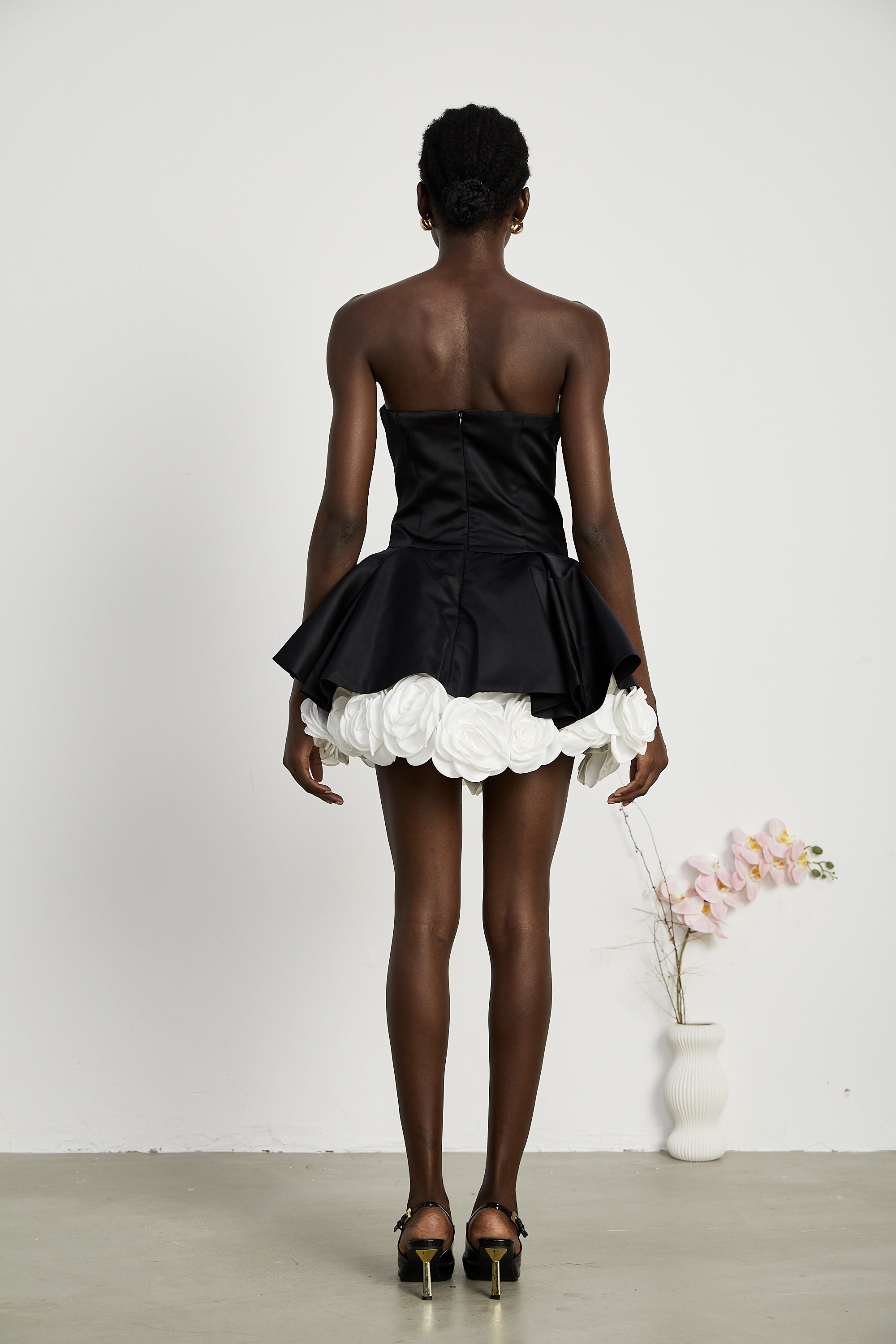 فستان لوسي الأسود القصير بدون حمالات مع طبقات من بتلات الزهور