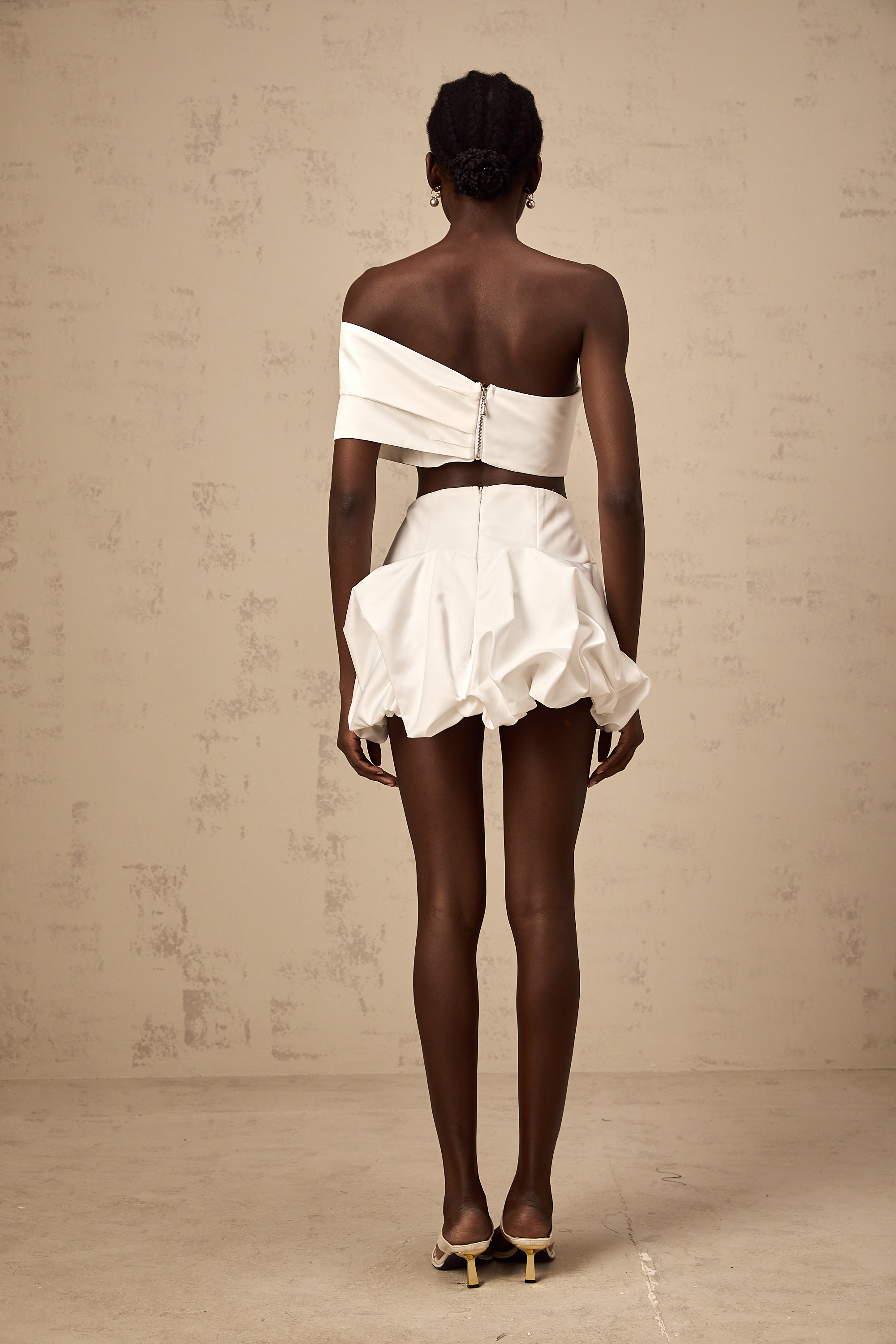 طقم هونورين المكون من بلوزة وتنورة مزينة بثنيات زهرية باللون الأبيض