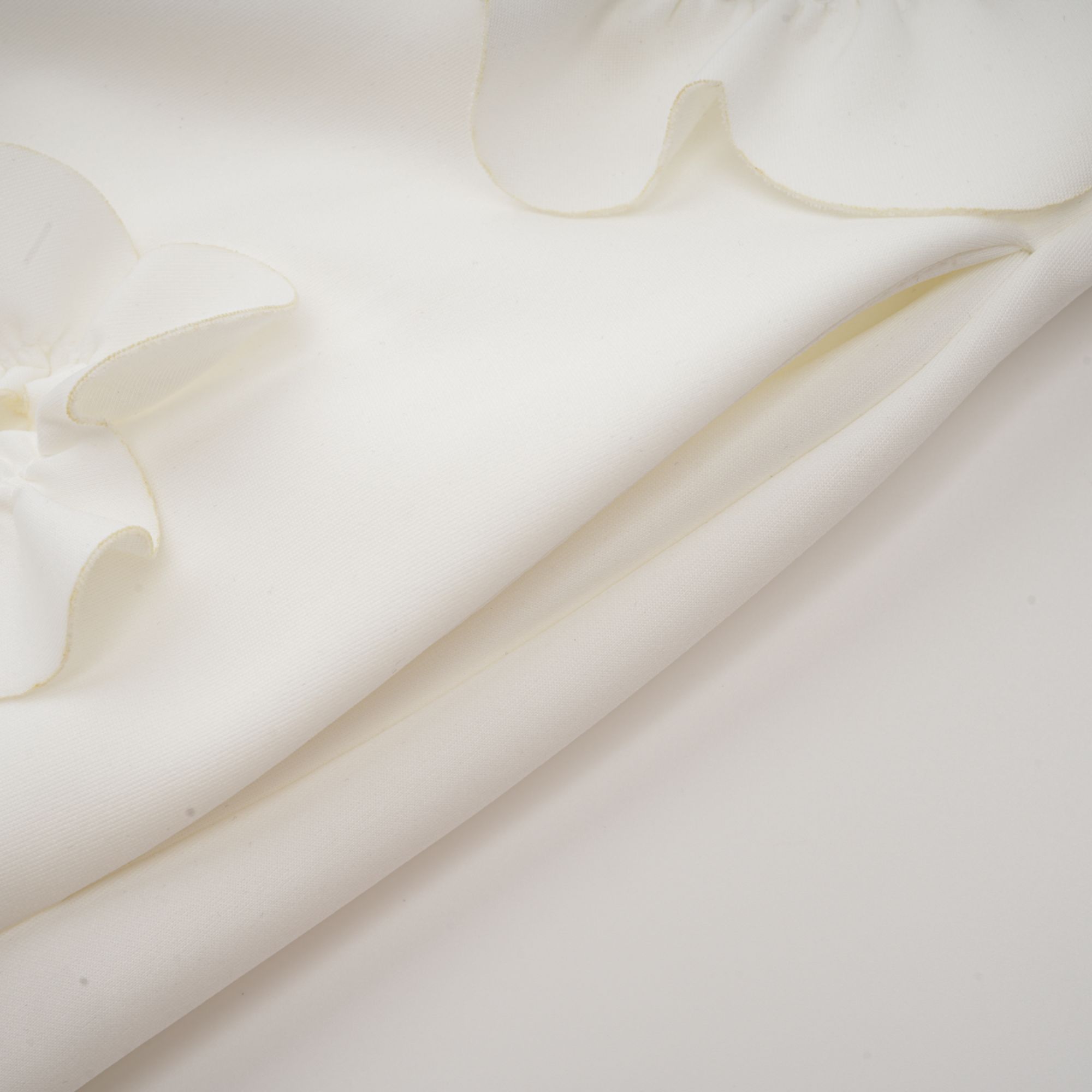 فستان ماكسي أبيض بدون أكمام من ماجالي مع زينة زهور صناعية وربطة عنق على شكل فيونكة