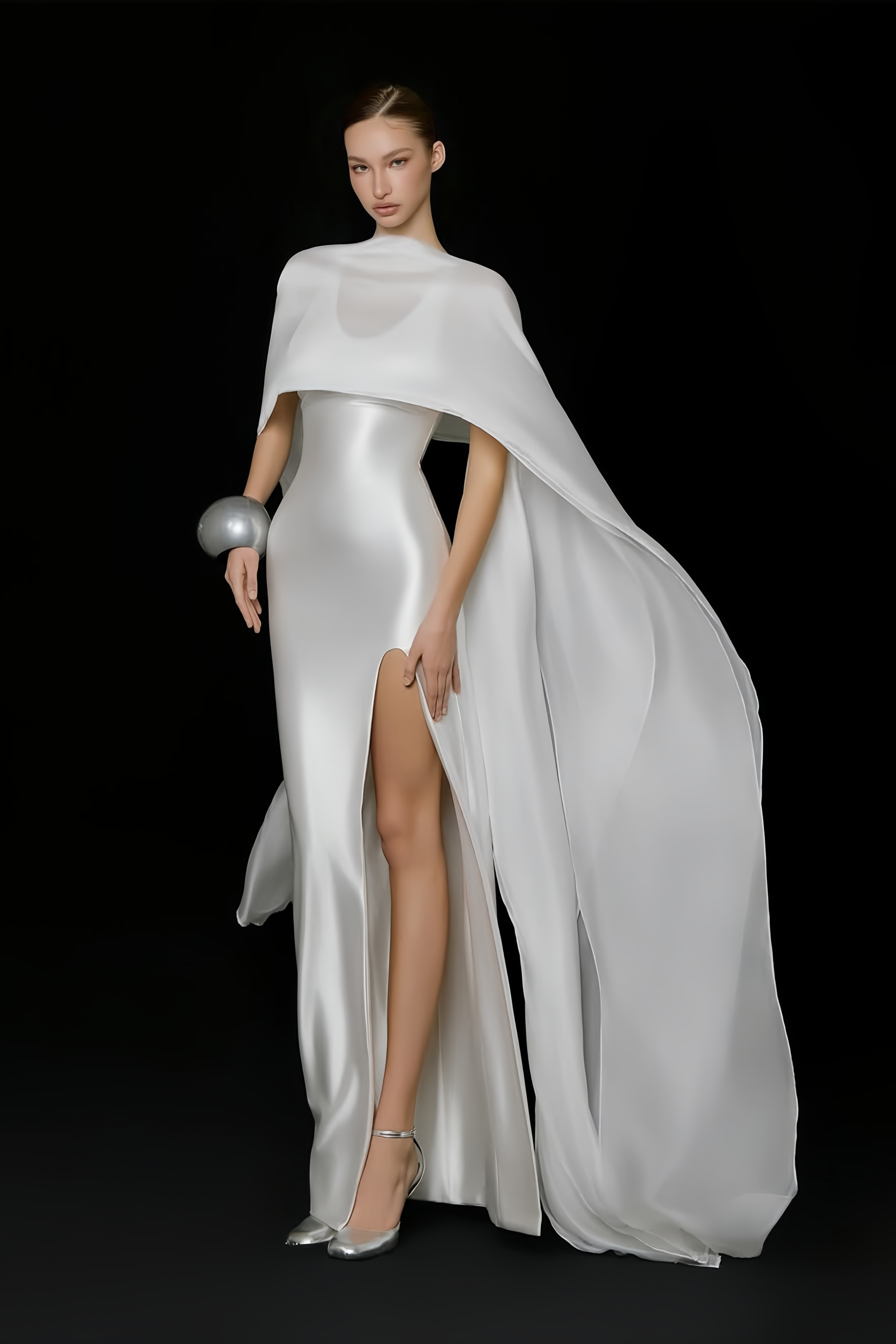 Élégante robe longue en satin blanc, accompagnée d'une longue cape assortie et d'une fente haute sur la jambe
