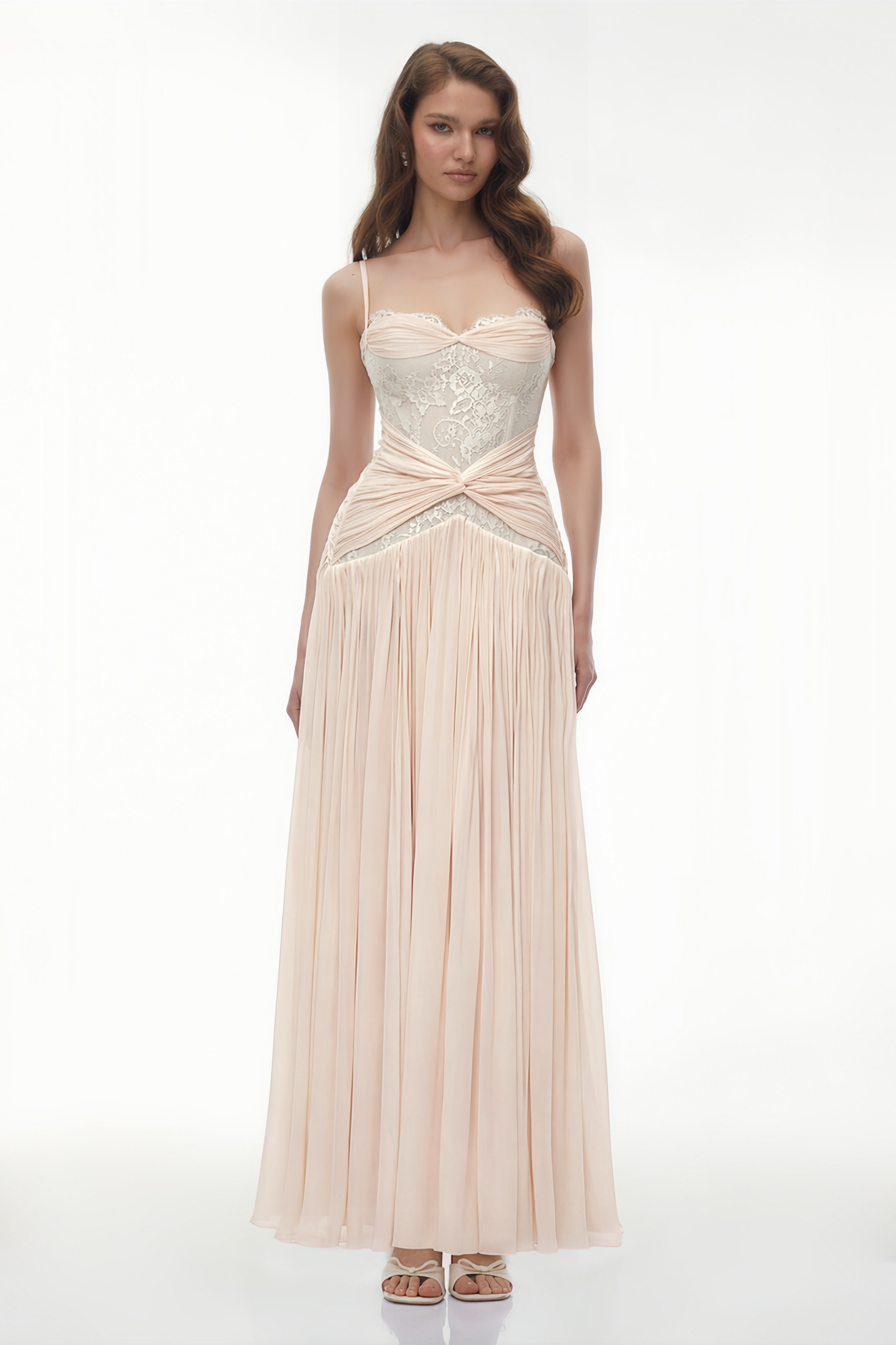 Robe longue rose pâle composée d'un corsage en dentelle blanche transparente, d'une ceinture drapée et torsadée, et d'une jupe finement plissée