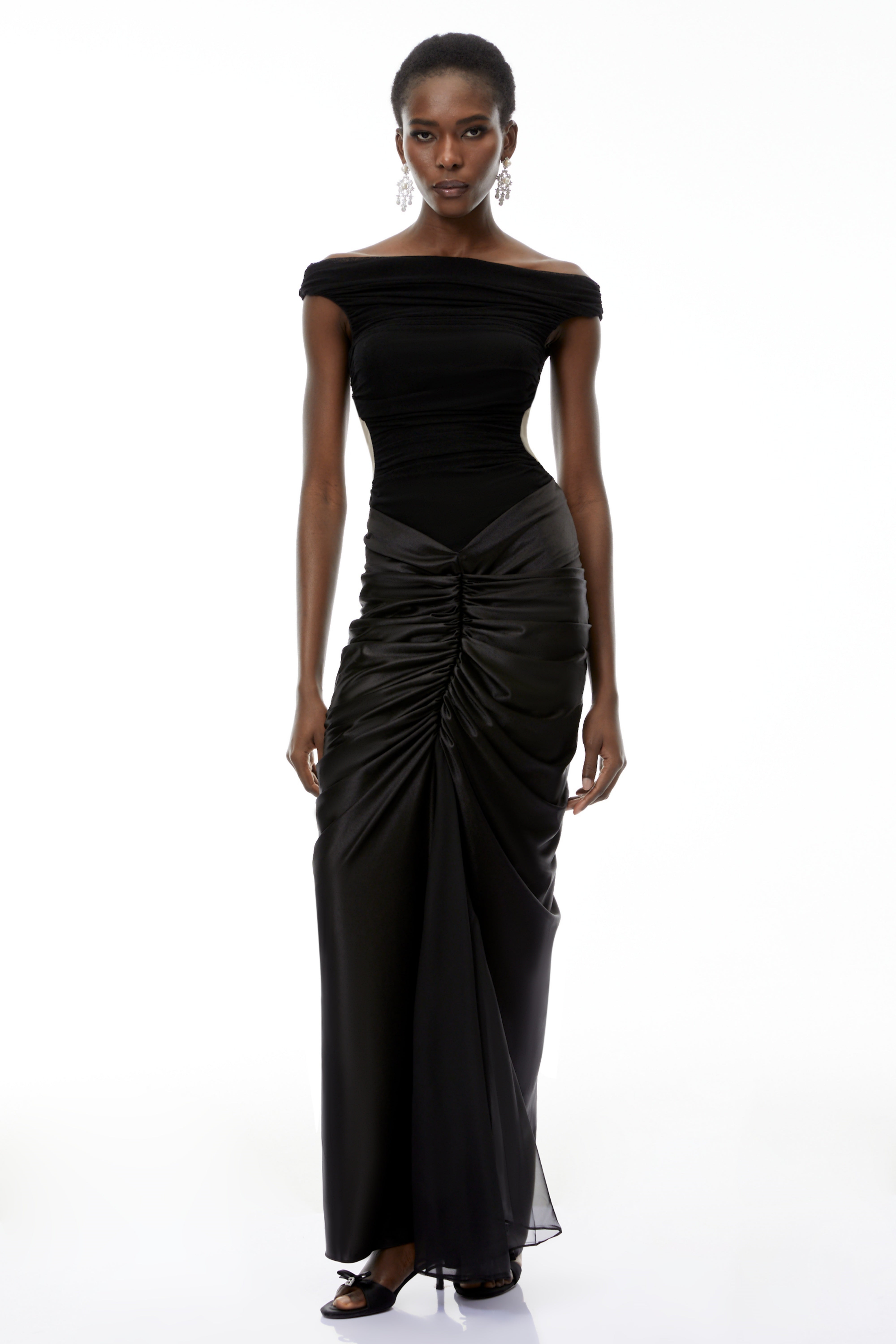 فستان طويل من إيدن باللون الأسود، مكشوف الكتفين ومزين بكشكشة