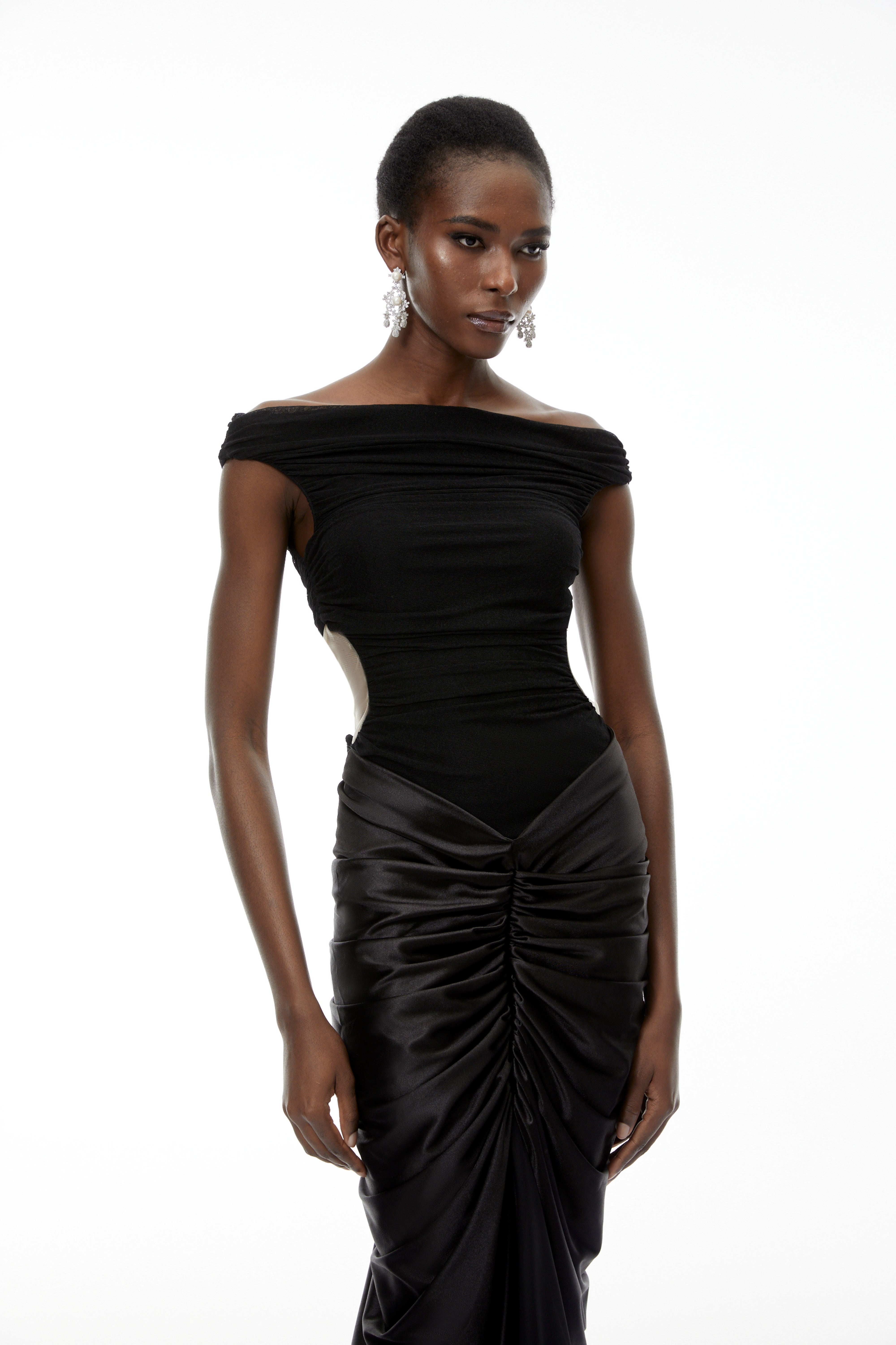 فستان طويل من إيدن باللون الأسود، مكشوف الكتفين ومزين بكشكشة