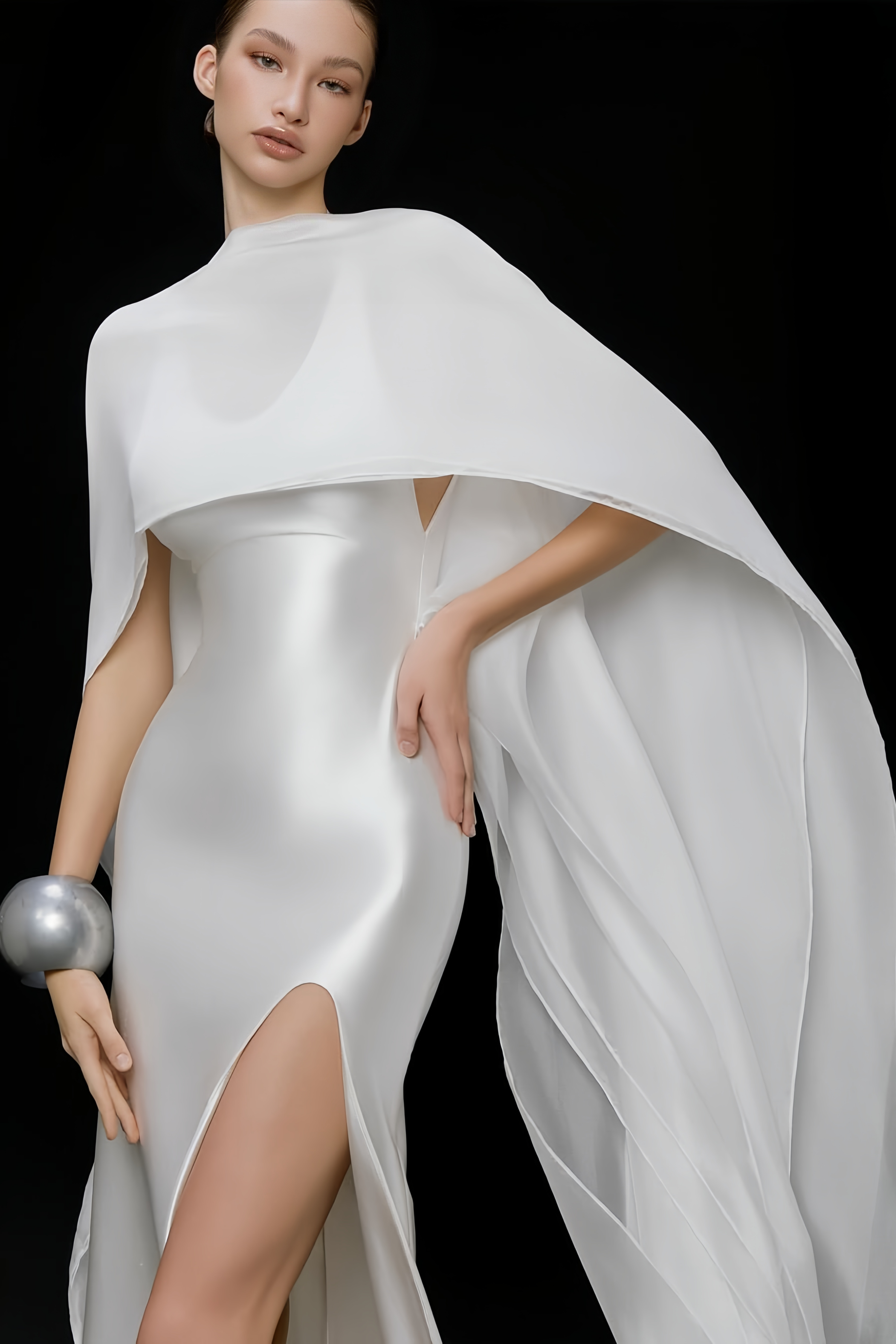 Élégante robe longue en satin blanc, accompagnée d'une longue cape assortie et d'une fente haute sur la jambe