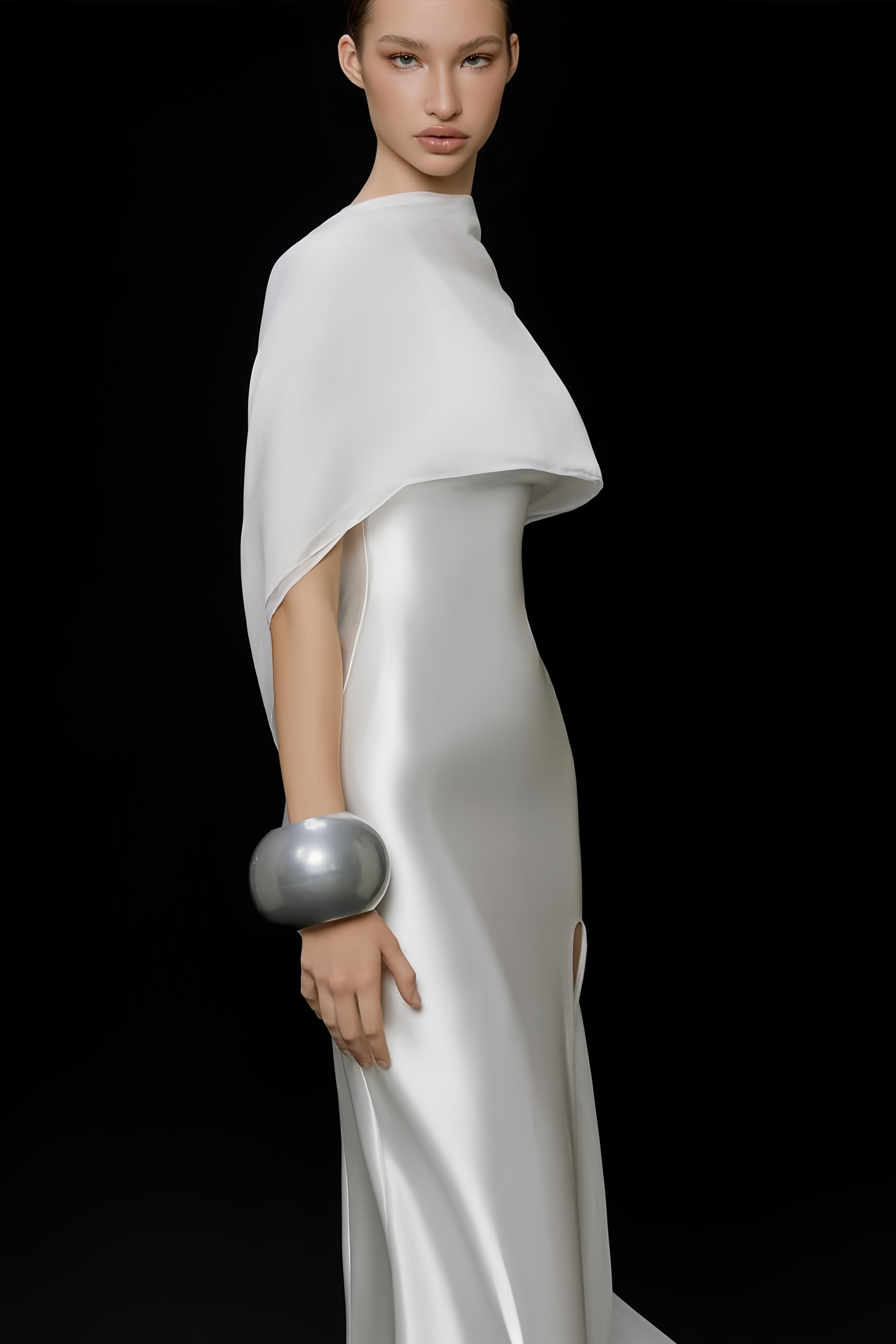 Élégante robe longue en satin blanc, accompagnée d'une longue cape assortie et d'une fente haute sur la jambe